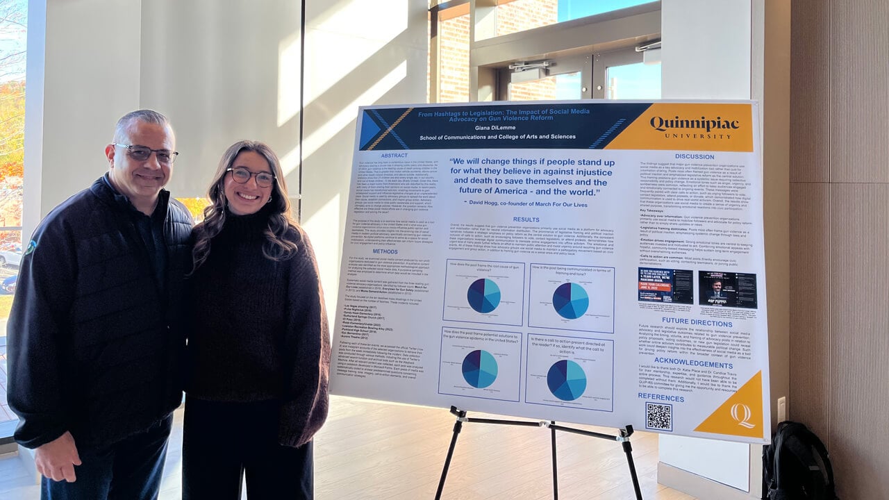 Giana DiLemme posing next to her poster with a man