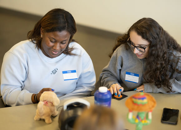 Two students collaborate at a table with toys