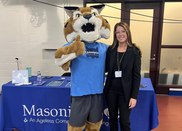 A female Masonicare employee posing for a photo with Boomer the Mascot